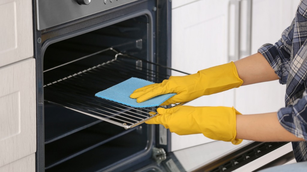 Woman cleaning oven in kitchen closeup picture id942141666